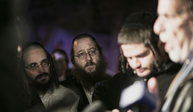 Orthodox Jewish people listen to N.Y. state Assemblyman Dov Hikind speak in Monsey, N.Y., Sunday, Dec. 29, 2019, following a stabbing late Saturday during a Hanukkah celebration. A man attacked the celebration at a rabbi&#x27;s home north of New York City late Saturday, stabbing and wounding several people before fleeing in a vehicle, police said. (AP Photo/Allyse Pulliam)