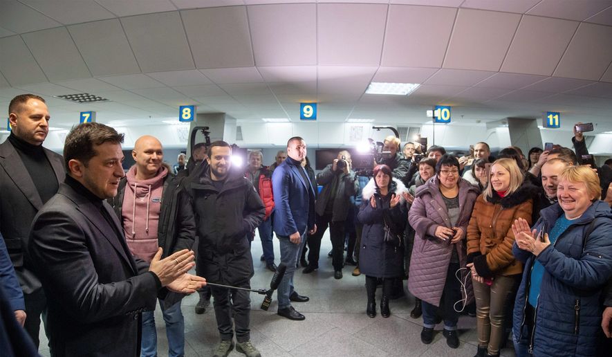 In this photo provided by the Ukrainian Presidential Press office, Ukrainian President Volodymyr Zelenskiy, left, speaks to relatives of Ukrainian prisoners waiting their arrival after being released after a prisoner exchange at Boryspil airport, outside Kyiv, Ukraine, Sunday, Dec. 29, 2019. Ukrainian forces and Russia-backed rebels in eastern Ukraine have exchanged 200 prisoners in a move aimed at ending their five-year war. The swap is part of an agreement brokered this month at a summit of the leaders of Ukraine, Russia, Germany and France. (Ukrainian Presidential Press Office via AP)