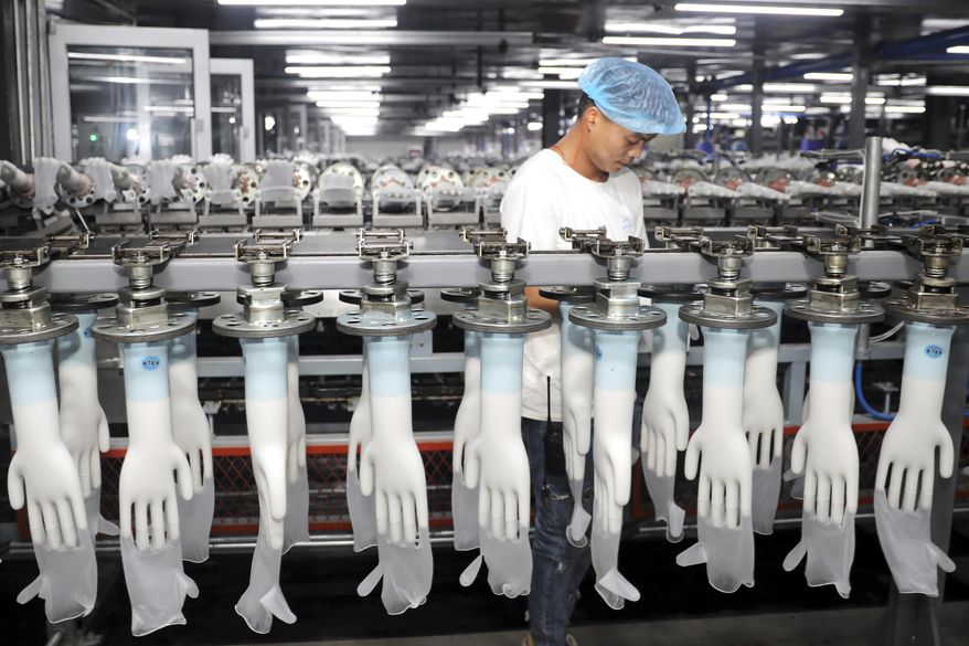 FILE - In this Aug. 14, 2019, file photo, a man works on a production line in a medical gloves factory in Suixi in central China's Anhui province. An official survey of manufacturers shows that factory activity in China held steady in December. (Chinatopix via AP, File)