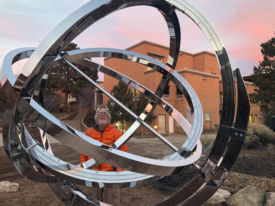 In this Dec. 11, 2019 photo Bill Donahue, a retired teacher and director of laboratories at St. John's College, uses an armillary sphere to track planetary rotations and explore the history of astronomy in Santa Fe, N.M. The unique precision-steel replica of an instrument created by Danish astonomer Tycho Brahe was commissioned by graduates of the college where students trace the evolution of math and science from early civilizations. (AP Photo/Morgan Lee)