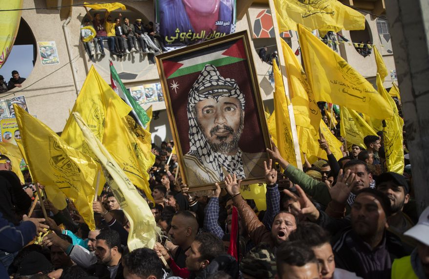 A Palestinian carries a picture of the late Palestinian leader Yasser Arafat, during a rally marking the 55th anniversary of the Fatah movement founding, in Gaza City, Wednesday, Jan. 1, 2020. Fatah is a secular Palestinian party and former guerrilla movement founded by Arafat, in Gaza City, Wednesday, Jan. 1, 2020. (AP Photo/Khalil Hamra)