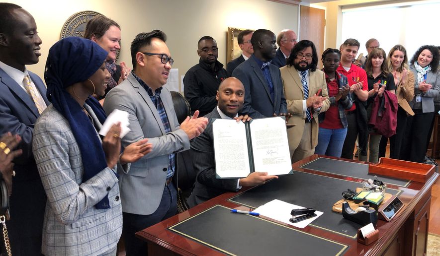 Shelby County, Tenn., Mayor Lee Harris, seated at desk, holds up a letter reaffirming Tennessee&#39;s largest county&#39;s commitment to keep resettling refugees on Friday, Jan. 3, 2020, in Memphis, Tenn. (AP Photo/Adrian Sainz)