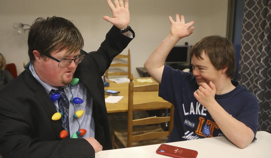 In this Monday, Dec. 9, 2019, photo, Luke Humble, right, and Conor Gunderson, left, high-five one another as they think about their grocery list in the kitchen at the new Luna Azul housing development for adults with disabilities, in Phoenix. Parents in Arizona, Wisconsin, Maryland and other states have launched housing developments for adults with disabilities in recent years. (AP Photo/Ross D. Franklin)