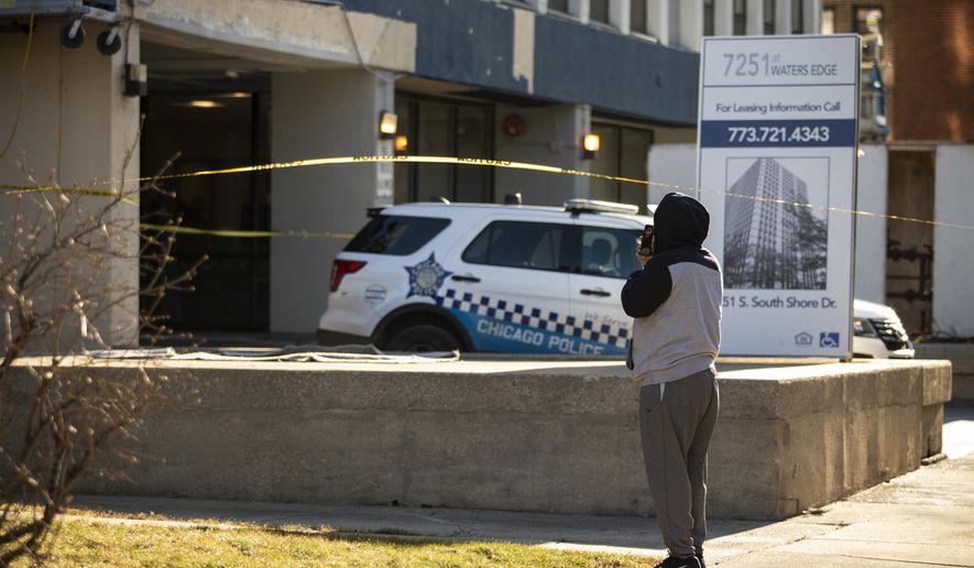 A neighbor takes pictures with his cell phone as Chicago Police investigate at a South Shore neighborhood high-rise apartment building in the 7200 block of South South Shore Drive, Thursday morning, Jan. 2, 2020. Chicago police say two toddlers are dead after a woman stabbed her father, left one of the children in a bathtub and then jumped from an 11th-floor apartment with the other child. (Ashlee Rezin Garcia/Chicago Sun-Times via AP)