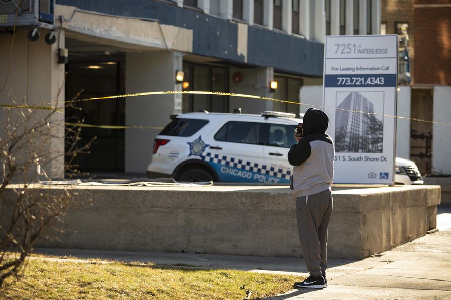 A neighbor takes pictures with his cell phone as Chicago Police investigate at a South Shore neighborhood high-rise apartment building in the 7200 block of South South Shore Drive, Thursday morning, Jan. 2, 2020. Chicago police say two toddlers are dead after a woman stabbed her father, left one of the children in a bathtub and then jumped from an 11th-floor apartment with the other child. (Ashlee Rezin Garcia/Chicago Sun-Times via AP)