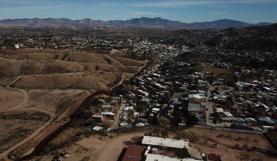 The U.S. border fence separates Nogales, Mexico, right, from sister city Nogales, Arizona, left, Friday, Jan. 3, 2020. Dozens of asylum seekers pushed back into Mexico by the United States tried Friday to get their bearings still unsure of how they would travel some 350 miles to their court dates in El Paso, subsist for months in this unfamiliar border city or return to their distant homelands. (AP Photo/Luis Enrique Castillo)