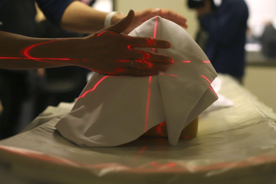 Tania Grgurich, clinical associate professor of diagnostic imaging at Quinnipiac University, puts the skull of the skeletal remains under CT scan machine at the university's Center for Medicine, Nursing and Health Sciences, Friday, Jan. 3, 2020, in North Haven, Conn. The skeletal remains were found underneath a 18th century home while the owners were renovating the basement in December. (AP Photo/Chris Ehrmann)