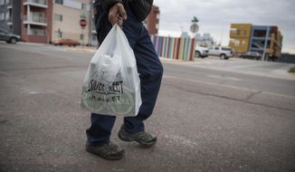 In this Jan. 10, 2019, file photo a shopper carries groceries in a plastic bag after shopping at the Silver Street Market in downtown Albuquerque, N.M. Businesses in New Mexico&#39;s largest metropolitan area are preparing for rules that will take effect with the start of the new year that call for banning plastic bags. (Roberto E. Rosales/The Albuquerque Journal via AP, File)