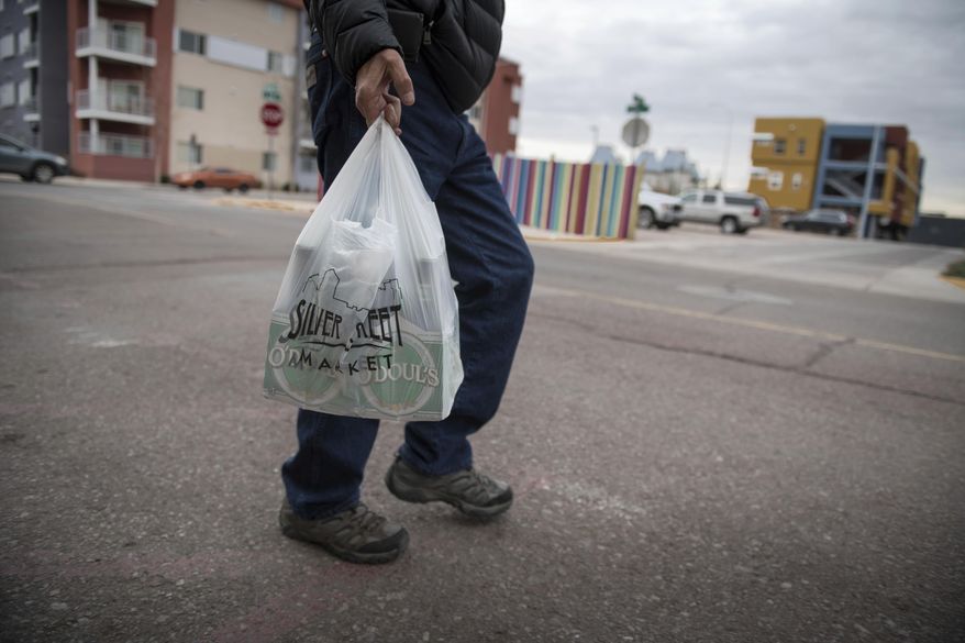 In this Jan. 10, 2019, file photo a shopper carries groceries in a plastic bag after shopping at the Silver Street Market in downtown Albuquerque, N.M. Businesses in New Mexico&#39;s largest metropolitan area are preparing for rules that will take effect with the start of the new year that call for banning plastic bags. (Roberto E. Rosales/The Albuquerque Journal via AP, File)