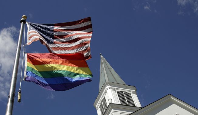 In this April 19, 2019, file photo, a gay pride rainbow flag flies along with the U.S. flag in front of the Asbury United Methodist Church in Prairie Village, Kan. United Methodist Church leaders are proposing creation of a separate division that would let more traditional denominations break away because of the disagreement with churches over the UMC’s official stance on gay marriage. (AP Photo/Charlie Riedel, File)