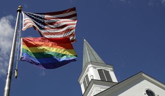 FILE - In this April 19, 2019, file photo, a gay pride rainbow flag flies along with the U.S. flag in front of the Asbury United Methodist Church in Prairie Village, Kan., United Methodist Church leaders are proposing creation of a separate division that would let more traditional denominations break away because of the disagreement with churches over the UMC’s official stance on gay marriage. (AP Photo/Charlie Riedel, File)