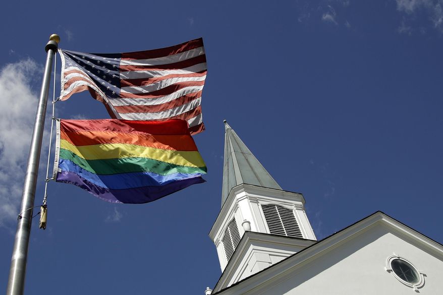 In this April 19, 2019, file photo, a gay pride rainbow flag flies along with the U.S. flag in front of the Asbury United Methodist Church in Prairie Village, Kan. United Methodist Church leaders are proposing creation of a separate division that would let more traditional denominations break away because of the disagreement with churches over the UMC’s official stance on gay marriage. (AP Photo/Charlie Riedel, File)