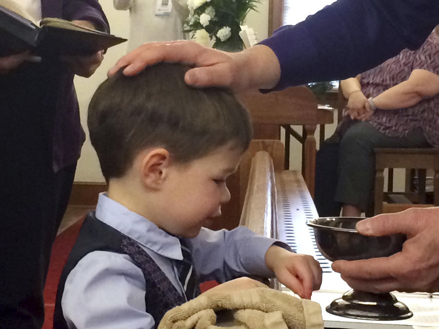 The Rev. Donn Stephens puts his hand on the head of Malcolm Kuhn, 4, of New Berlin, who was baptized during the final service of New Salem United Methodist Church, Sunday, Dec. 29, 2019. Malcolm is the son of Martin and Kate Fleming-Kuhn. The congregation was founded in 1823, making it likely Sangamon County's second-oldest church behind First United Methodist. Members voted Nov. 12 to close the church. (Steven Spearie/The State Journal-Register via AP)