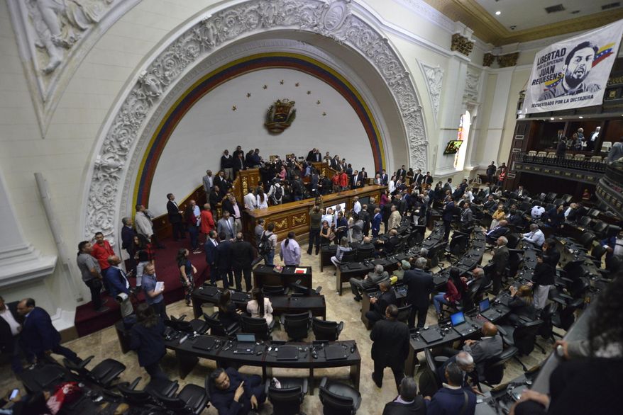 Lawmakers move about the chamber as they swear-in lawmaker Luis Parra as National Assembly president after many opposition lawmakers, including opposition Assembly President Juan Guaidó, were blocked by police from entering the session to participate in the vote for new leadership in Caracas, Venezuela, Sunday, Jan. 5, 2020. Without a quorum, there was no vote for Parra, while the opposition, who enjoy a comfortable majority, immediately denounced the impromptu session as invalid. (AP Photo/Matias Delacroix)
