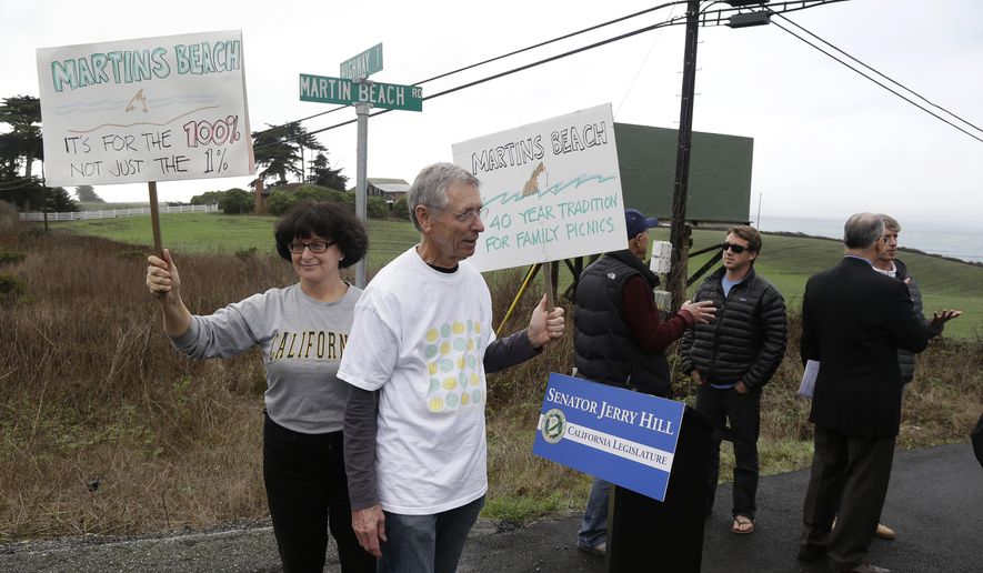 FILE - In this Feb. 10, 2014, file photo, Julie Graves, left, of Albany, Calif., and Chris Adams, second from left, of Berkeley, Calif., hold up signs in support of a beach access bill near Martin's Beach in Half Moon Bay, Calif. California officials are suing a billionaire who has been fighting for more than a decade to keep a secluded beach to himself, a move designed to ensure that the public always has access the scenic stretch of sand. The lawsuit was filed Monday, Jan. 6, 2020, on behalf of the California State Lands Commission and Coastal Commission. (AP Photo/Eric Risberg, File)