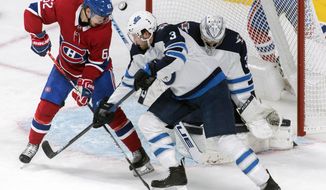 Montreal Canadiens&#39; Artturi Lehkonen (62) moves in against Winnipeg Jets goaltender Connor Hellebuyck as Jets&#39; Tucker Poolman (3) defends during second-period NHL hockey game action in Montreal, Monday, Jan. 6, 2020. (Graham Hughes/The Canadian Press via AP)
