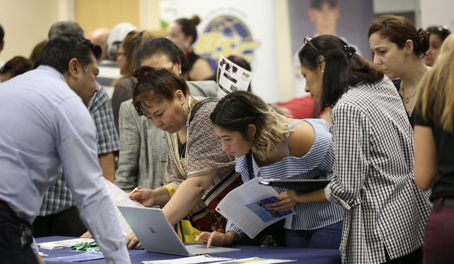 In this Sept. 18, 2019, file photo job applicants look at jobs available at Florida International University during a job fair in Miami. On Wednesday, Jan. 8, 2020, payroll processor ADP reported on how many jobs its survey estimates U.S. companies added in December. (AP Photo/Lynne Sladky, File)