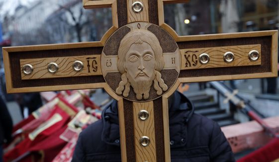A man holds a cross during a rally in central Belgrade, Serbia, Wednesday, Jan. 8, 2020. Thousands of Serbs have answered a call by the Serbian Orthodox Church to stage a protest against alleged suppression of religious and other rights of minority Serbs in neighboring countries. (AP Photo/Darko Vojinovic)