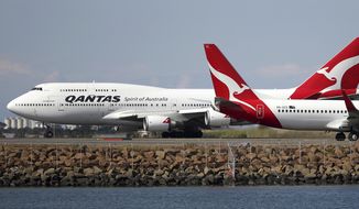In this Aug. 20, 2015, file photo, two Qantas planes taxi on the runway at Sydney Airport in Sydney, Australia. Some Asian airlines have rerouted flights to the Middle East to avoid Iranian airspace, amid escalated tensions over the United States’ assassination of a prominent Iranian commander in Iraq. (AP Photo/Rick Rycroft, File)