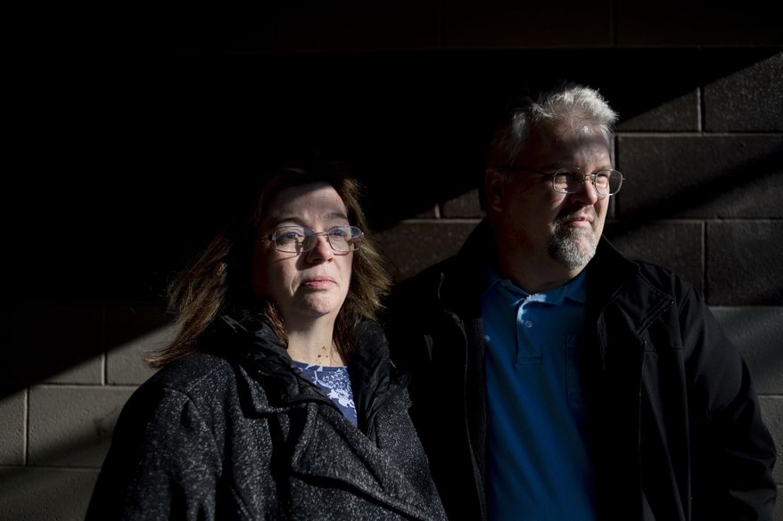 FIL E- In this Monday, Jan. 6, 2020, file photo, Pam and Karl Bacon pose for a picture at Elms Park in Swartz Creek, Mich., days after their son Kevin Bacon, of Swartz Creek, was found dead. A public defender filed a notice to seek an insanity defense for Mark Latunski, a mid-Michigan man accused in the slaying and mutilation of Kevin Bacon he met online. Shiawassee County Court documents say attorney Douglas Corwin also filed a motion Tuesday afternoon for a forensic evaluation for Mark Latunski, WNEM-TV reported. (Jake May/The Flint Journal via AP)
