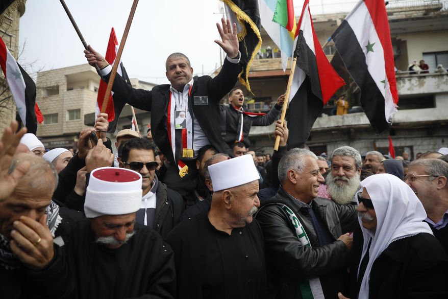 Druze men carry Sidqi al-Maqt, left, and Amal Abu Saleh as they wave Syrian flags upon their release from Israeli prison in the village of Majdal Shams on the border with Syria Friday, Jan. 10, 2020. (AP Photo/Ariel Schalit)