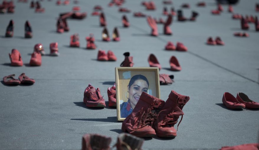A portrait of Eugenia Machuca Campos sits amid women's red shoes placed by activists to protest violence against women in the Zocalo, Mexico City's main plaza, Saturday, Jan. 11, 2020. According to her sister, Campos' ex-boyfriend is serving time in jail for her Oct. 2017 murder in the State of Mexico. (AP Photo/Christian Palma)