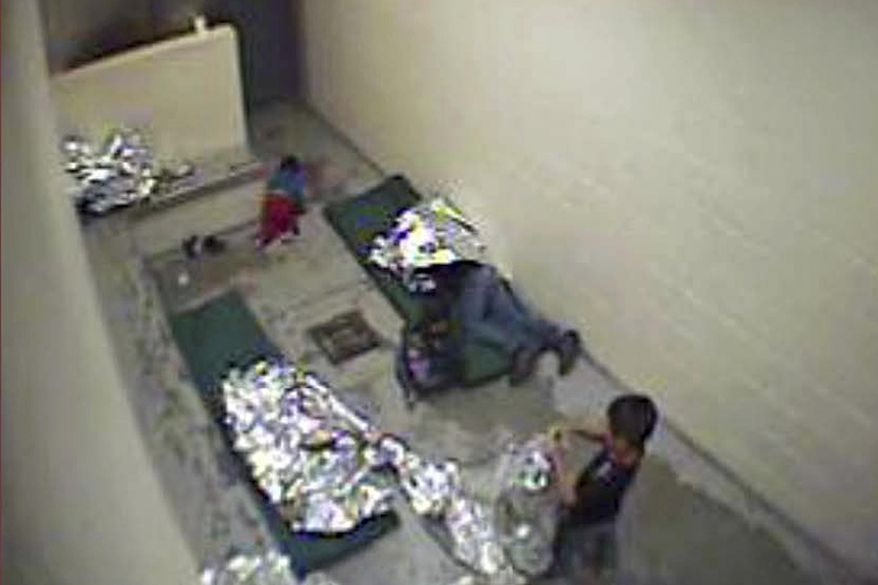 This Sept. 2015, file image made from U.S. Border Patrol surveillance video shows a child crawling on the concrete floor near the bathroom area of a holding cell, and a woman and children wrapped in Mylar sheets at a U.S. Customs and Border Protection station in Douglas, Ariz. A years-old lawsuit challenging detention conditions in several of the Border Patrol’s Arizona stations will go to trial Monday, Jan. 13, 2020, as the agency as a whole has come under fire following several migrant deaths. The lawsuit was first filed in June 2015 and applies to eight Border Patrol facilities in Arizona where attorneys say migrants are held in unsafe and inhumane conditions. (U.S. Border Patrol via AP, File)