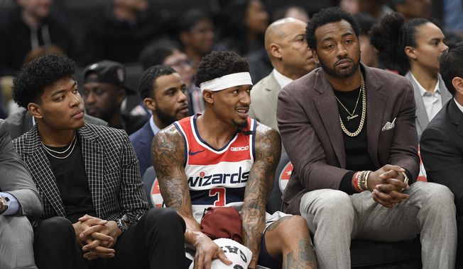 Washington Wizards forward Rui Hachimura, left, of Japan, guard Bradley Beal, center, and guard John Wall, right, watch from the bench during the first half of an NBA basketball game against the Utah Jazz, Sunday, Jan. 12, 2020, in Washington. (AP Photo/Nick Wass)