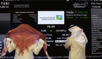 FILE- In this Dec. 11, 2019, file photo, the Saudi stock market officials watch the stock market screen displaying Saudi Arabia&#39;s state-owned oil company Aramco after the debut of Aramco&#39;s initial public offering (IPO) on the Riyadh&#39;s stock market in Riyadh, Saudi Arabia. Saudi Arabian oil company Aramco&#39;s initial public offering raised $29.4 billion, more than previously announced after the company said Sunday it used a so-called &amp;quot;greenshoe option&amp;quot; to sell an additional 450 million shares to satiate investor demand. (AP Photo/Amr Nabil)