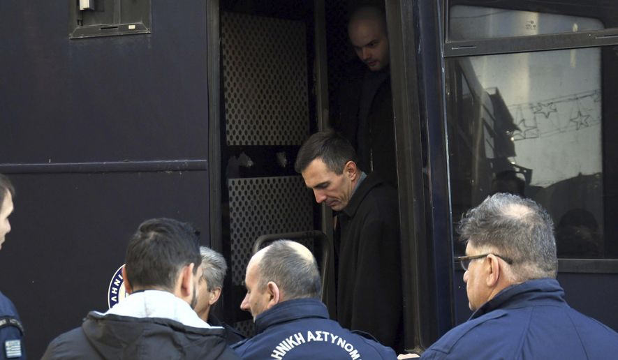 Greek police officers escort two of the seven suspects involved in the fatal beating of Texan tourist Bakari Henderson as they disembark a police bus at a court house in Patras city, western Greece, Wednesday, Jan. 8, 2020. A Greek court has postponed the retrial of seven suspects on murder charges over the 2017 fatal beating of a Texan tourist on an island resort. (AP Photo/Giannis Androutsopoulos)