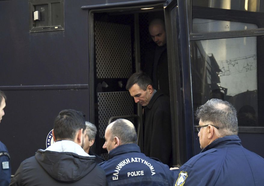 Greek police officers escort two of the seven suspects involved in the fatal beating of Texan tourist Bakari Henderson as they disembark a police bus at a court house in Patras city, western Greece, Wednesday, Jan. 8, 2020. A Greek court has postponed the retrial of seven suspects on murder charges over the 2017 fatal beating of a Texan tourist on an island resort. (AP Photo/Giannis Androutsopoulos)