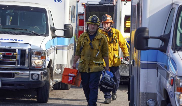 Firefighter/paramedics walk between a group of ambulances parked by Park Avenue Elementary School after jet fuel was dumped on the school in Cudahy, Calif., Tuesday, Jan. 14, 2020. A pair of people, one a homeless man, were found dead in a man-dug cave Sunday in Northridge, near Los Angeles. White powder containing fentanyl was also found. (Scott Varley/The Orange County Register via AP)