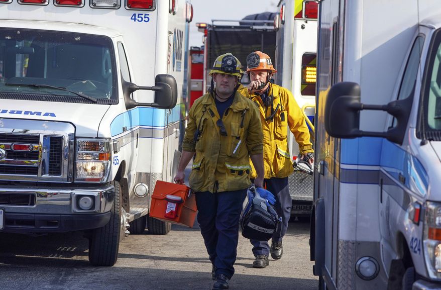Firefighter/paramedics walk between a group of ambulances parked by Park Avenue Elementary School after jet fuel was dumped on the school in Cudahy, Calif., Tuesday, Jan. 14, 2020. A pair of people, one a homeless man, were found dead in a man-dug cave Sunday in Northridge, near Los Angeles. White powder containing fentanyl was also found. (Scott Varley/The Orange County Register via AP)
