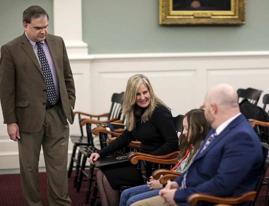 Kate Frederick waits with her son Devon, and her husband Brad, right, as they await the Supreme Court to start on Tuesday, January 14, 2020 in Concord, NH. Frederick's lawyer, Benjamin King is at far left. Frederick was fired from her former employer, the New Hampshire Department of Health and her wrongful termination case has played out for years in local courts and at the State House. (Geoff Forester/The Concord Monitor via AP)
