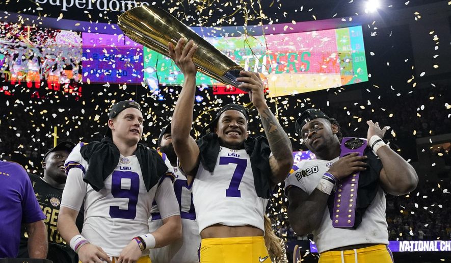 LSU safety Grant Delpit holds the trophy as quarterback Joe Burrow, left, and linebacker Patrick Queen look on after a NCAA College Football Playoff national championship game against Clemson, Monday, Jan. 13, 2020, in New Orleans. LSU won 42-25. (AP Photo/David J. Phillip)