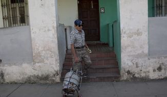 Alberto Perez, a 77-year-old retired man, leaves his home in the Sevillano neighborhood with an empty cooking gas tank as he departs for a shop where he will replace it with a full one in Havana, Cuba, Tuesday, Jan 14, 2020. The Cuban government is warning citizens to prepare for shortages of cooking gas due to Trump administration sanctions on the island.  (AP Photo/Ismael Francisco)