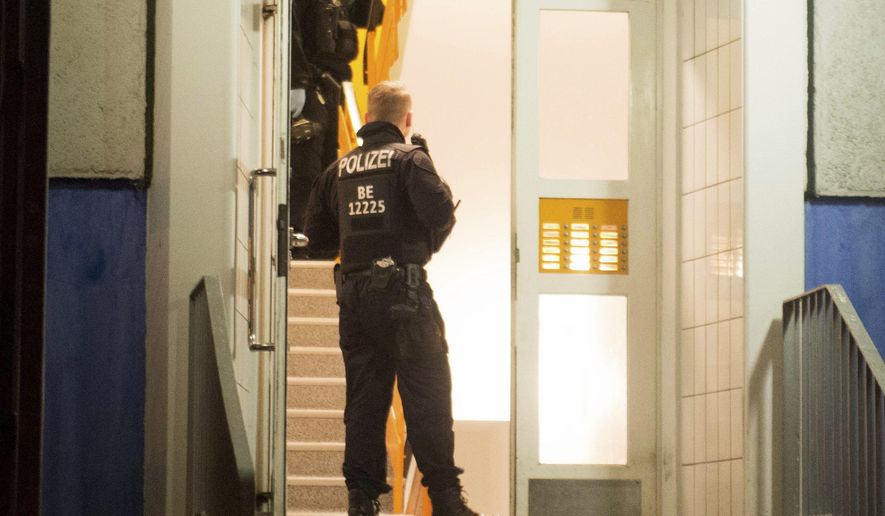 Police forces are standing in the hallway of an apartment building in Marzahn-Hellersdorf, Germany, Tuesday, Jan.14, 2020. In the early morning, investigators swarmed out in several federal states. The reason for the searches is the suspicion of preparation of a serious act of violence that endangers the state. (Dennis Brätsch/dpa via AP)