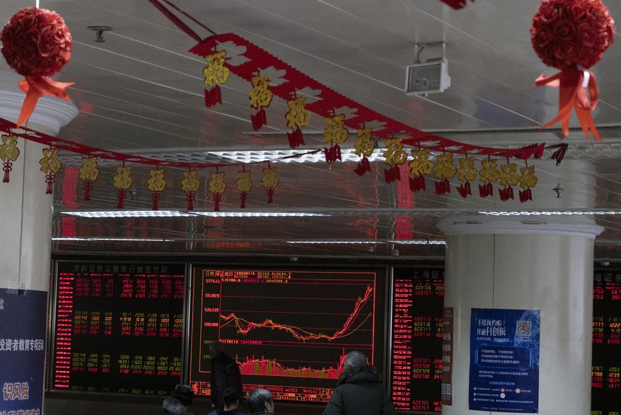 Investors monitor stock prices near Chinese New Year decorations hung up at a brokerage in Beijing Thursday, Jan. 16, 2020. Share prices are mixed in moderate trading in Asia after the U.S. and China signed a preliminary trade agreement that investors hope will bring better relations between the two biggest economies. (AP Photo/Ng Han Guan)