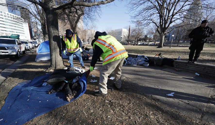 Officials clear a makeshift homeless camp citing a hazard to health early Wednesday, Jan. 15, 2020, in downtown Denver. More than 30 tents had been put up by homeless individuals in a park across from the State Capitol in the past two weeks. The park is being shut down because officials say it's become infested with rats. (AP Photo/David Zalubowski)