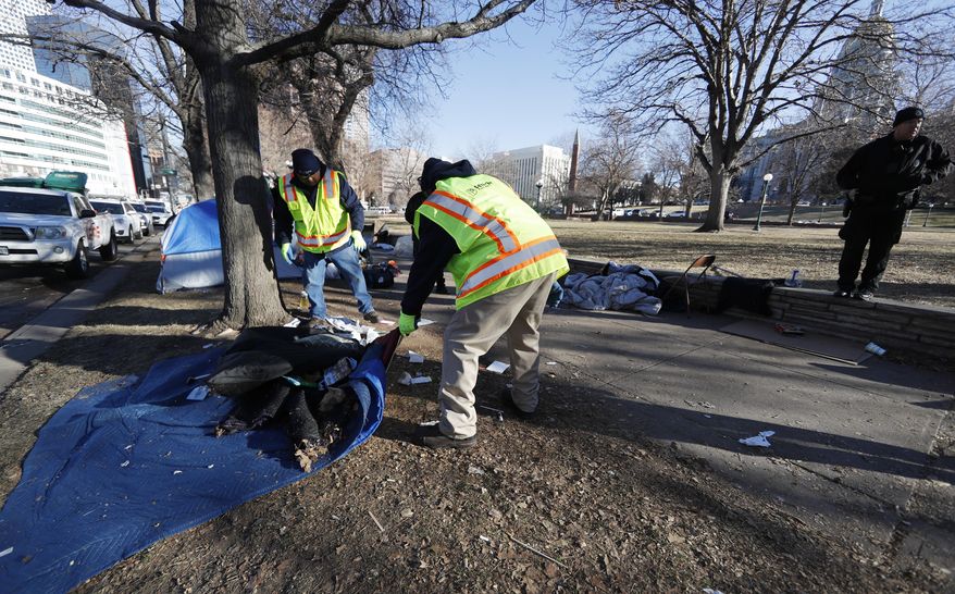 Officials clear a makeshift homeless camp citing a hazard to health early Wednesday, Jan. 15, 2020, in downtown Denver. More than 30 tents had been put up by homeless individuals in a park across from the State Capitol in the past two weeks. The park is being shut down because officials say it's become infested with rats. (AP Photo/David Zalubowski)