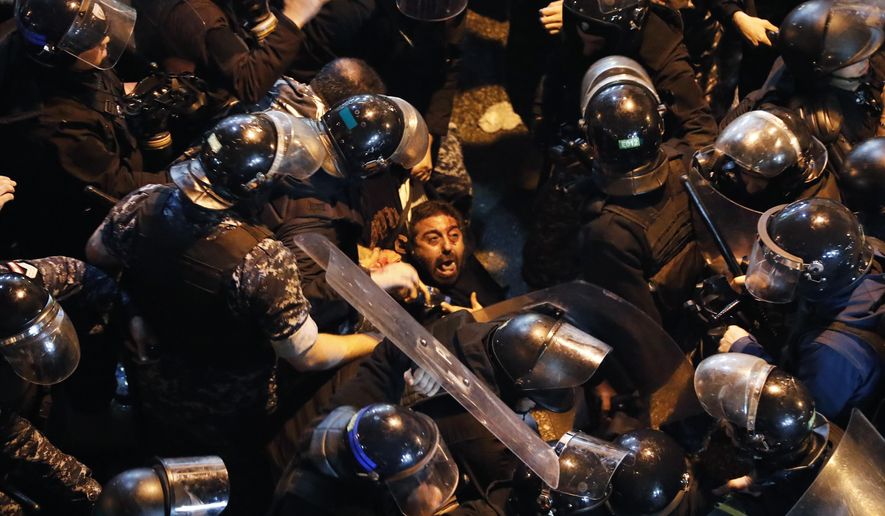 Riot police arrest an anti-government protester who was protesting outside a police headquarters demanding the release of those taken into custody the night before, outside the police headquarters, in Beirut, Lebanon, Wednesday, Jan. 15, 2020. Lebanese security forces arrested 59 people, the police said Wednesday, following clashes overnight outside the central bank as angry protesters vented their fury against the country's ruling elite and the worsening financial crisis. (AP Photo/Hussein Malla)