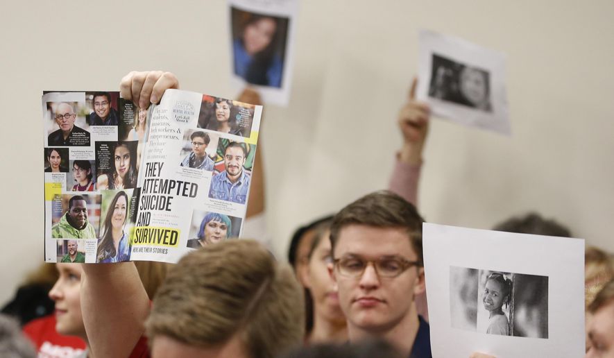FILE - In a Monday, Jan. 13, 2020 file photo, supporters of gun laws hold us photos of gun violence victims during a meeting of the Senate Judiciary committee at the Capitol in Richmond, Va. Gun-rights groups asked a judge Thursday, Jan. 16, 2020 to block Virginia Gov. Ralph Northam from banning guns on Capitol grounds during a massive pro-gun rally scheduled for Monday, Jan. 20, 2020. (AP Photo/Steve Helber, File)