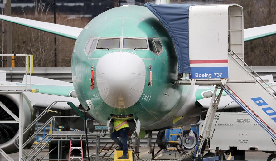 FILE - In this Dec. 16, 2019, file photo, a worker looks up underneath a Boeing 737 MAX jet, in Renton, Wash. Boeing has found a new software problem on its grounded 737 Max jetliner. The aircraft maker said, Friday, Jan. 17, 2020, it is making the necessary changes and working with the Federal Aviation Administration. (AP Photo/Elaine Thompson, File)