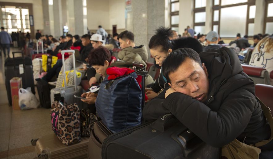 A traveler rests on his suitcase in a waiting room at the Beijing Railway Station in Beijing, Friday, Jan. 17, 2020. As the Lunar New Year approached, Chinese travelers flocked to train stations and airports Friday to take part in a nationwide ritual: the world&#x27;s biggest annual human migration. (AP Photo/Mark Schiefelbein)