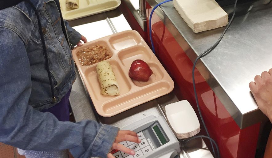 In this Thursday, May 4, 2017, file photo, a third-grader punches in her student identification to pay for a meal at Gonzales Community School in Santa Fe, N.M. The Trump administration is proposing a rollback of nutrition guidelines for federal school meals programs that had been promoted by Michelle Obama as part of her campaign to combat child obesity. (AP Photo/Morgan Lee, file)