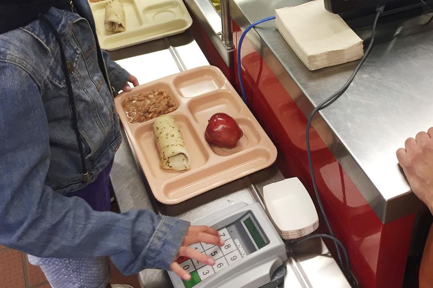 In this Thursday, May 4, 2017, file photo, a third-grader punches in her student identification to pay for a meal at Gonzales Community School in Santa Fe, N.M. The Trump administration is proposing a rollback of nutrition guidelines for federal school meals programs that had been promoted by Michelle Obama as part of her campaign to combat child obesity. (AP Photo/Morgan Lee, file)