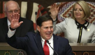 Arizona Republican Gov. Doug Ducey, front, raises his arm as he makes a pledge as he speaks during his State of the State address about Arizona&#39;s economy, new jobs, prison reform, and education as Senate president Karen Fann, R-Prescott, back right, and House Speaker Rusty Bowers, R-Mesa, back left, listen in on the opening day of the legislative session at the Capitol, Monday, Jan. 13, 2020, in Phoenix. (AP Photo/Ross D. Franklin)