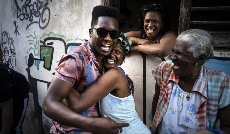 Cuban singer Cimafunk hugs a woman during the music conga through the streets of Old Havana within the activities of the 35th Havana Jazz Plaza festival in Havana, Cuba, Wednesday, Jan. 15, 2020. (AP Photo/Ramon Espinosa)