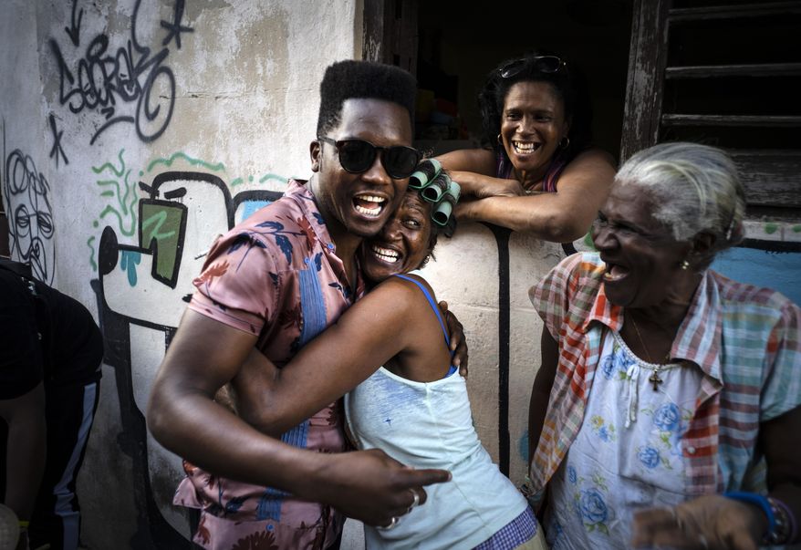 Cuban singer Cimafunk hugs a woman during the music conga through the streets of Old Havana within the activities of the 35th Havana Jazz Plaza festival in Havana, Cuba, Wednesday, Jan. 15, 2020. (AP Photo/Ramon Espinosa)