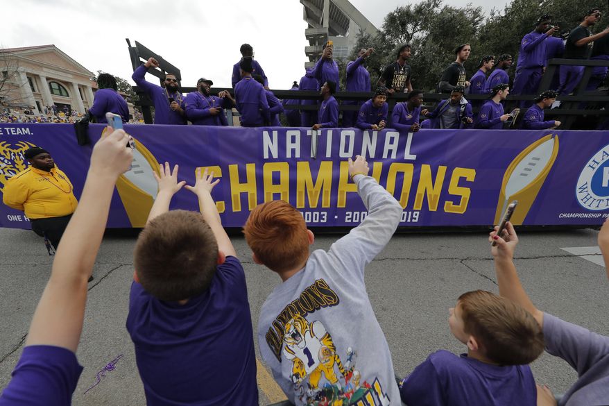 LSU fans cheer as players ride on floats during a parade celebrating LSU's NCAA college football championship, Saturday, Jan. 18, 2020, on the LSU campus in Baton Rouge, La. (AP Photo/Gerald Herbert)